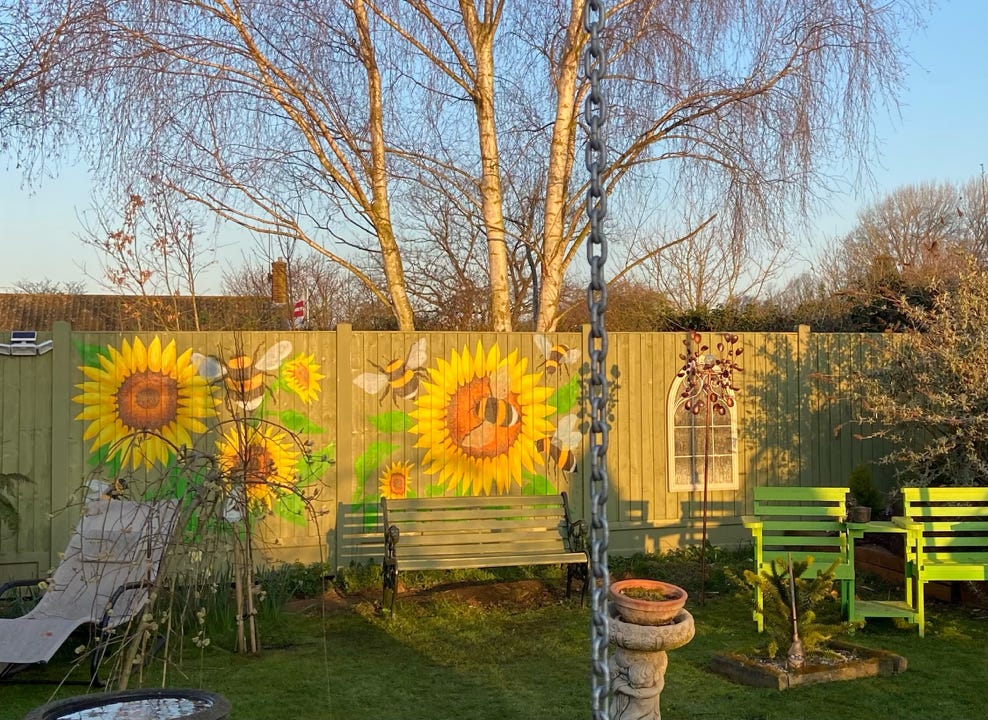 Sunflowers and bumblebees painted on a sunny garden fence